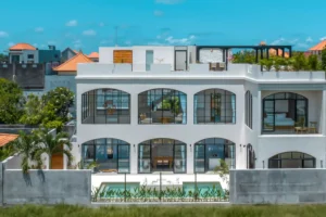 luxury Mansion Bali - A modern white villa with large arched windows and a private pool, highlighting upscale real estate investment opportunities offered by Coco Development Group in Bali.