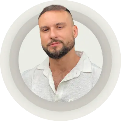 Portrait of a man with a close-cropped haircut and beard, wearing a white textured shirt, against a light beige circular background.
