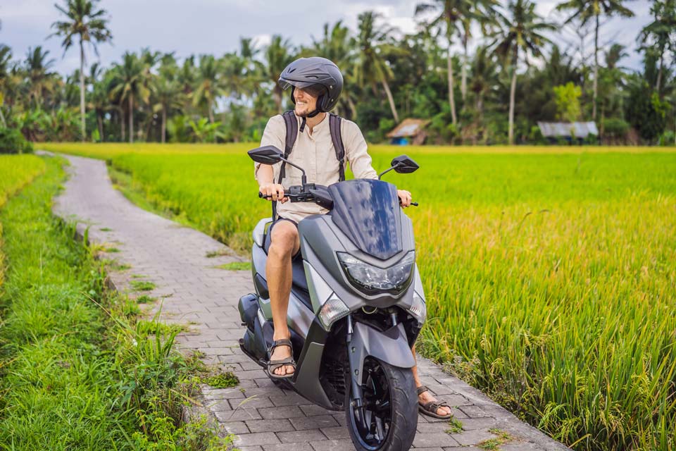 Male traveler on a bike among a rice field. Tourist travels to Bali