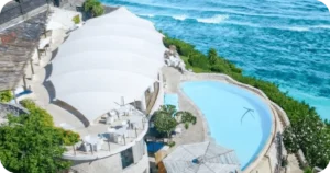 Aerial view of white-canopy restaurant and curved clifftop pool