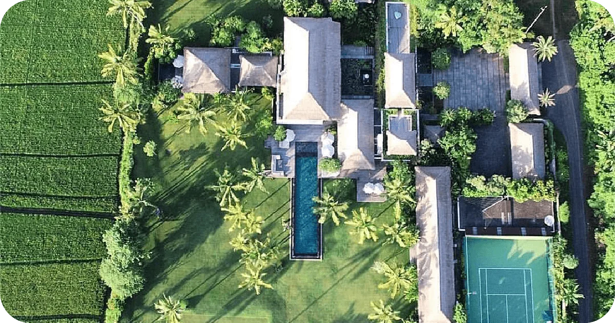 Aerial villa estate with long lap pool, lawns, tennis court and rice fields