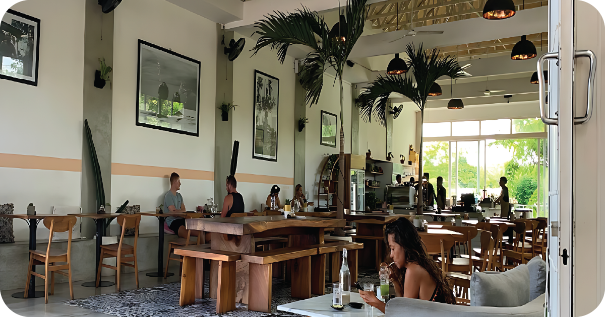 Airy café interior with wooden tables, palms, and open counter