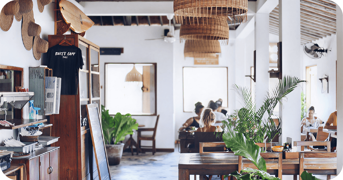 Airy tropical cafe interior with rattan lamps, plants, wooden tables