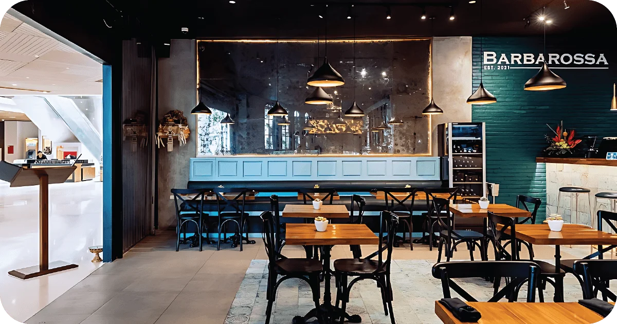 Barbarossa dining room with black chairs, teal brick wall, pendant lights