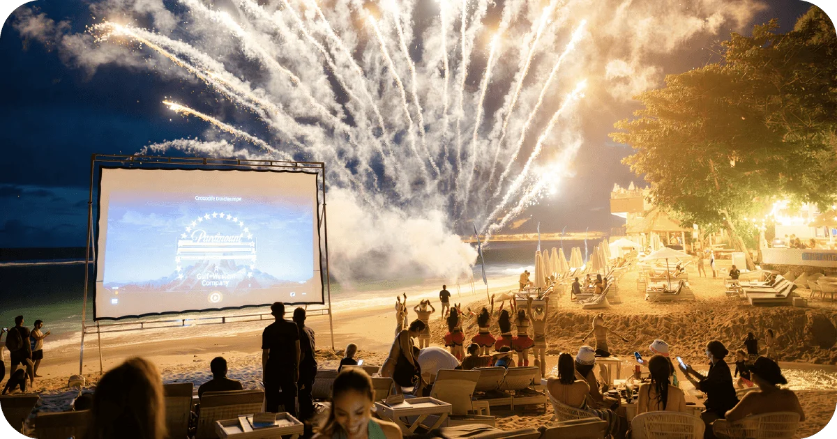 Beachfront movie night with fireworks and lounge seating under night sky