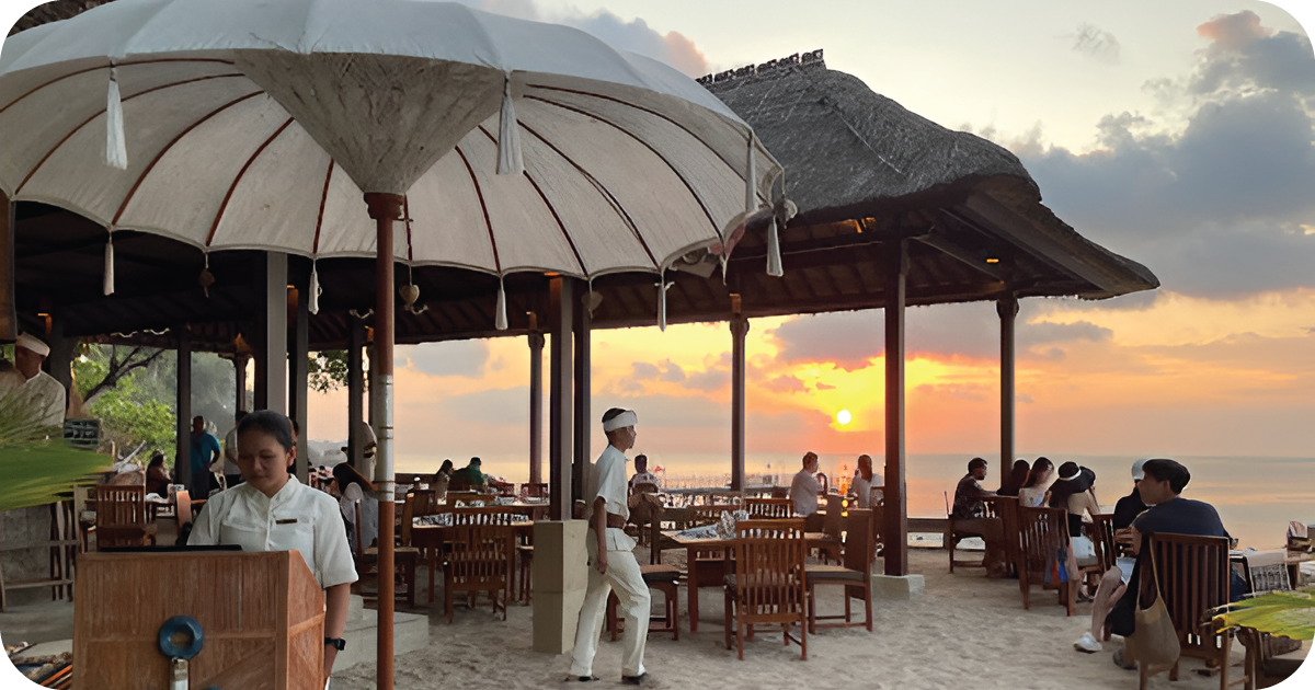 Beachfront restaurant with large umbrellas and wooden tables at sunset