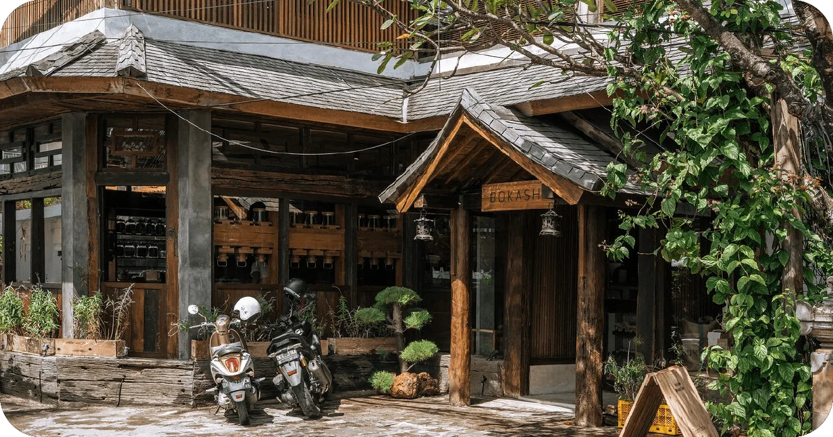 Bokashi exterior with rustic timber facade and parked scooters
