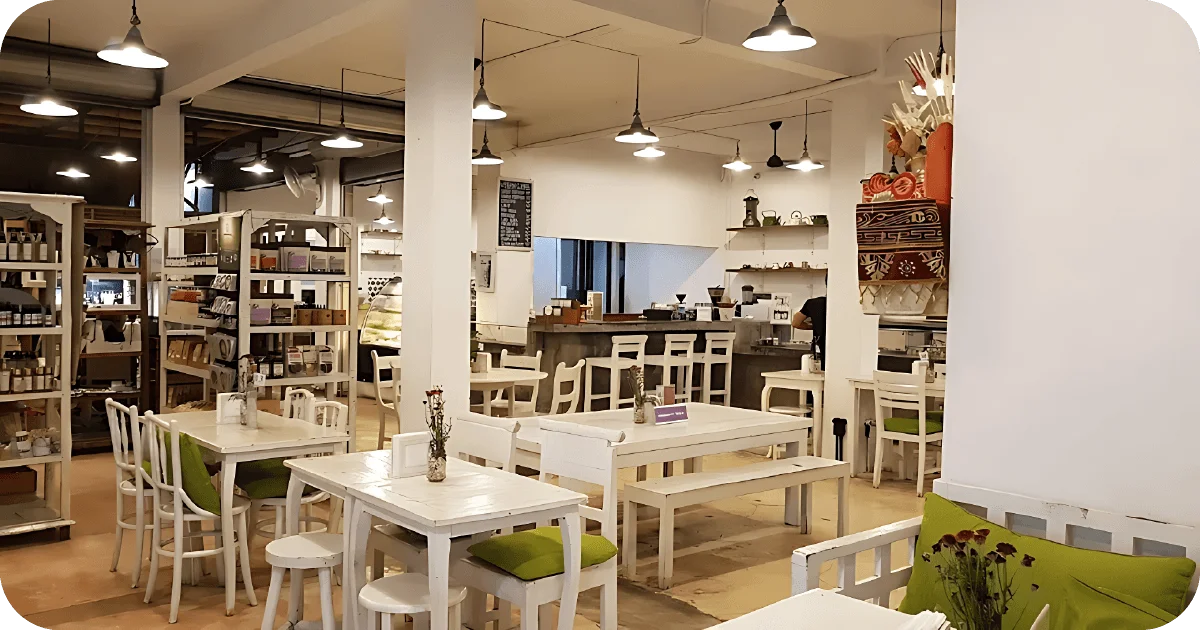 Bright café with white wooden tables, shelves, and counter service
