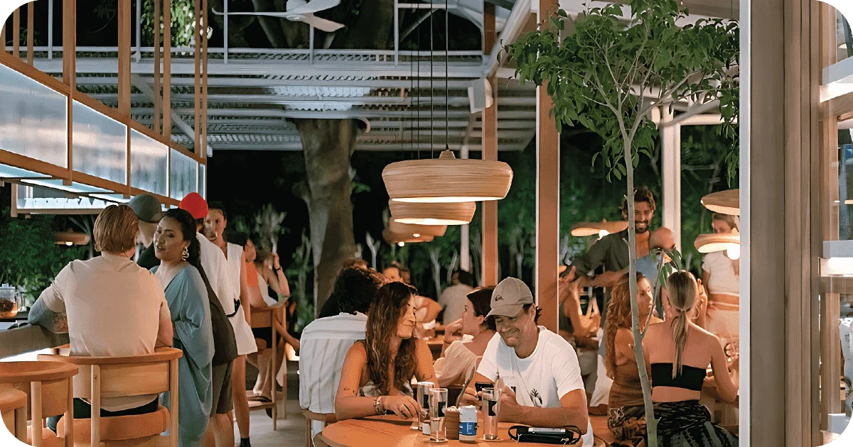 Bustling open-air dining with wood pendant lights and bar seating