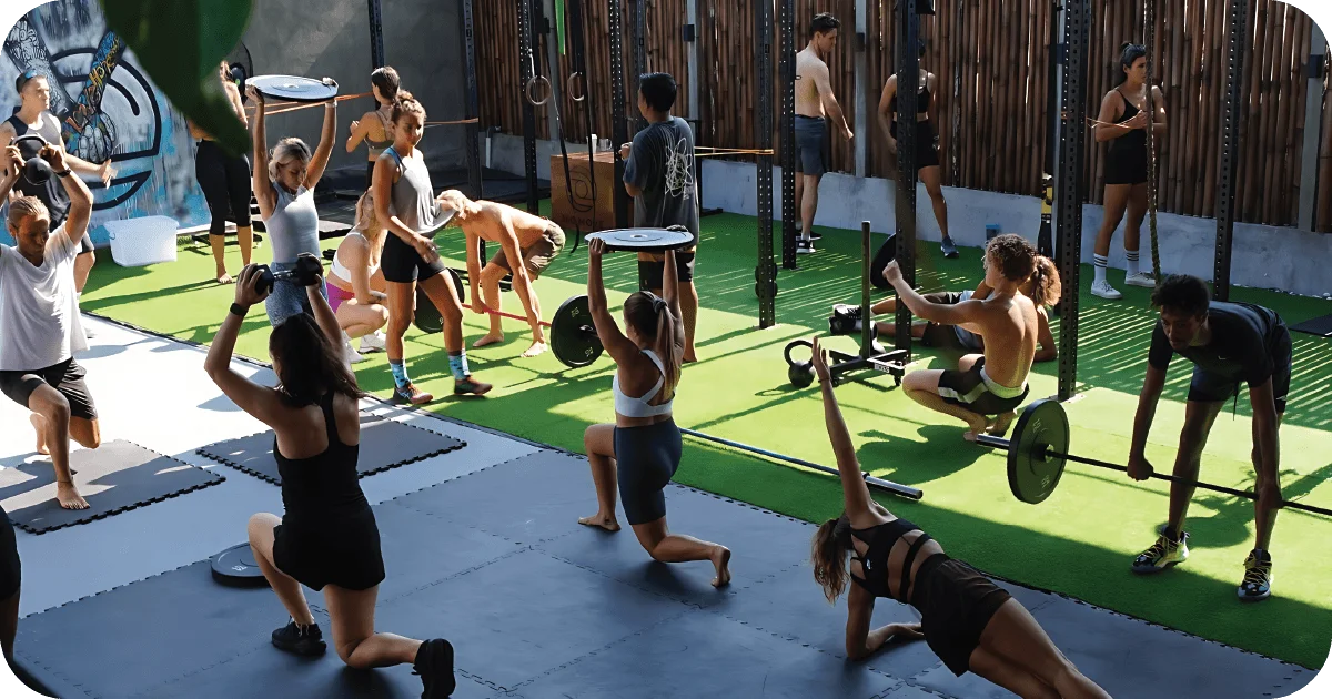 Busy outdoor functional training class with kettlebells, barbells and turf