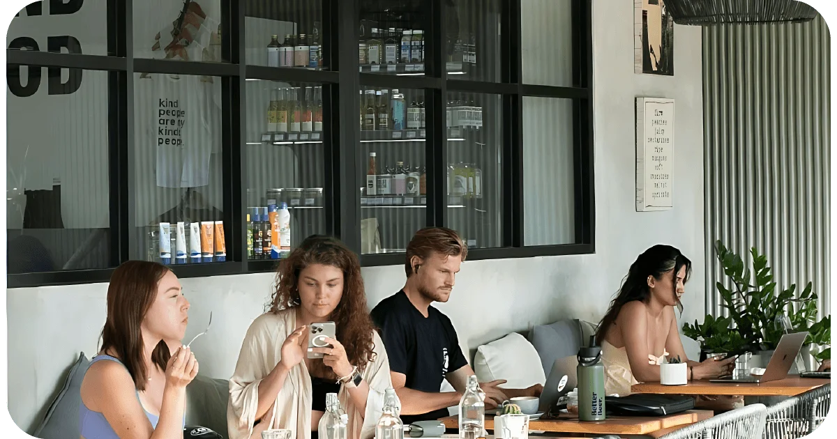 Cafe workspace seating with laptops beside retail shelves and large windows
