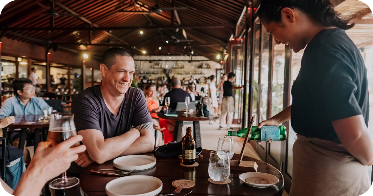 Casual dining room, server pouring water at set table
