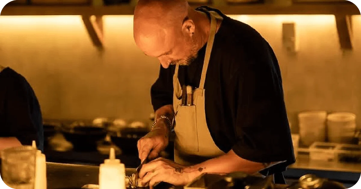 Chef prepping dishes at a warmly lit open kitchen