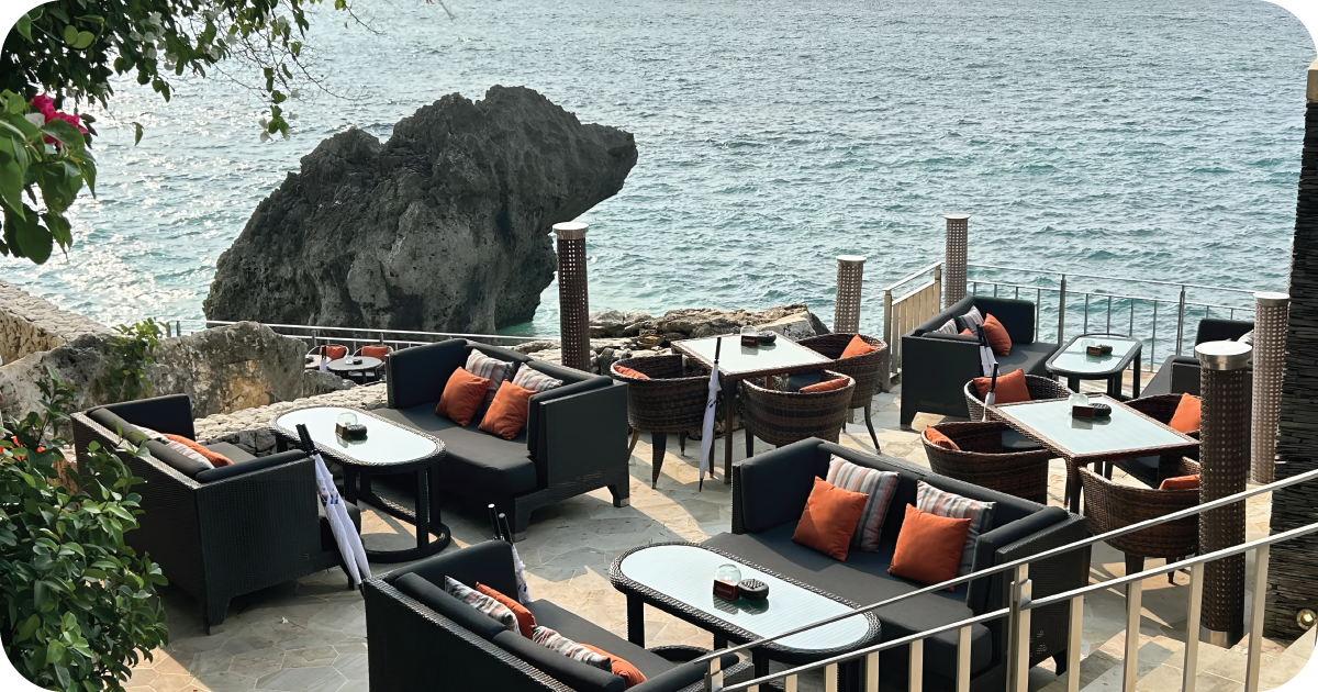 Cliffside oceanfront lounge seating with wicker sofas and orange cushions