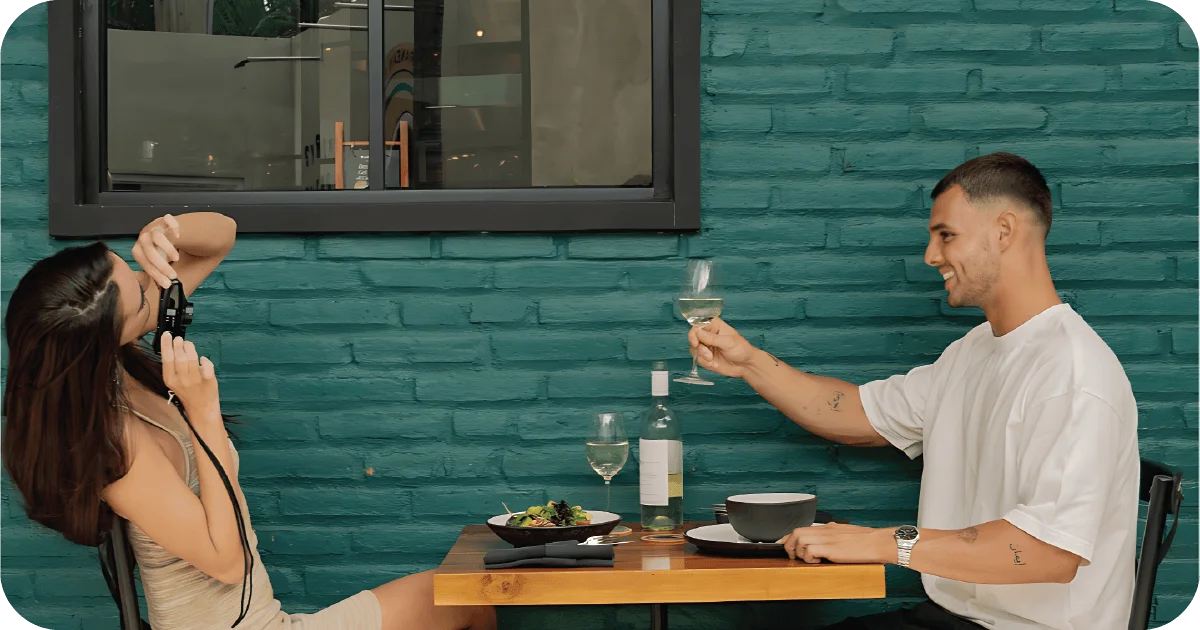 Couple toasting white wine over salad and soup at small table
