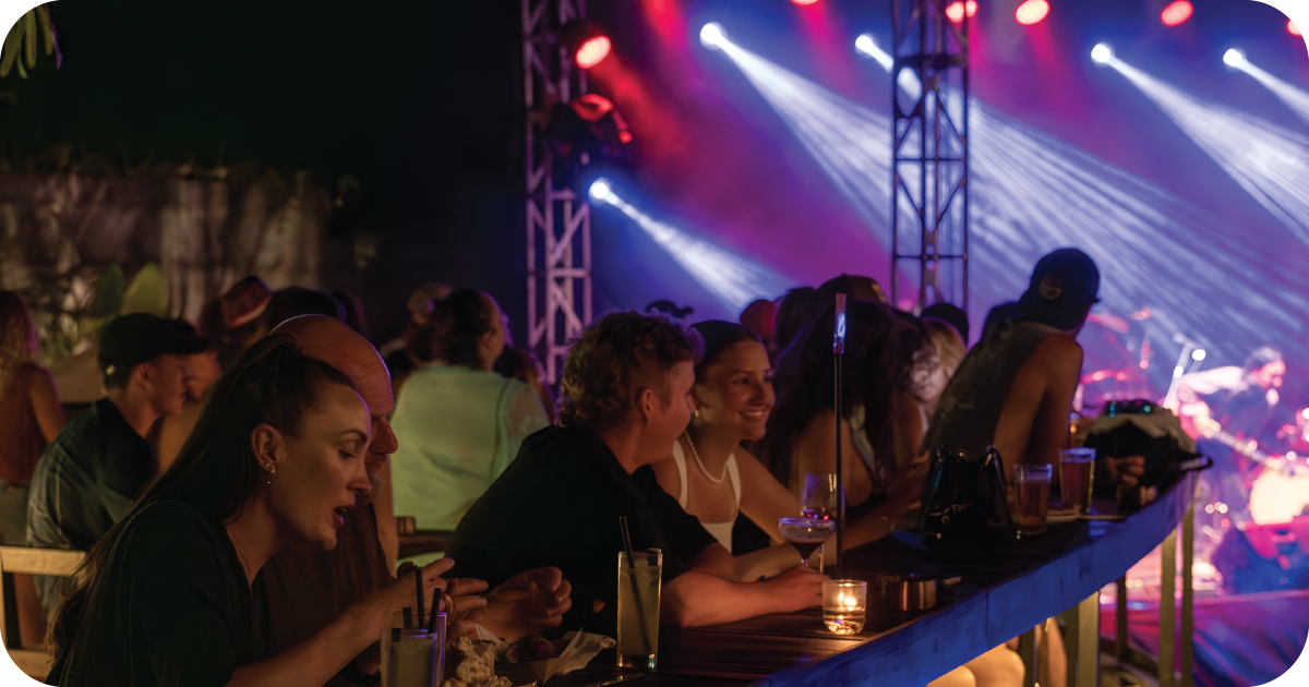 Crowded bar with stage lighting, cocktails and beers during live show