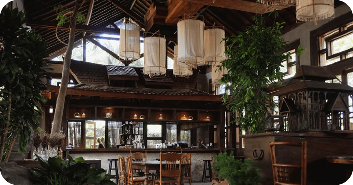 Daylit wooden bar with hanging lanterns and lush greenery