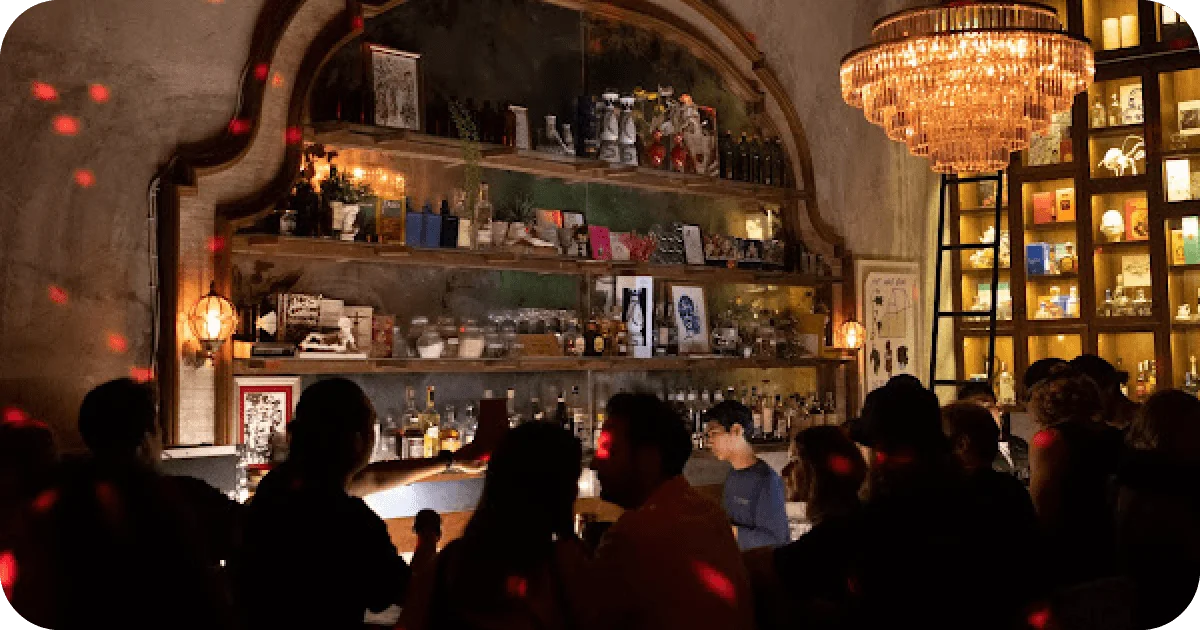 Dim cocktail bar with chandelier and backlit shelves in ornate arch