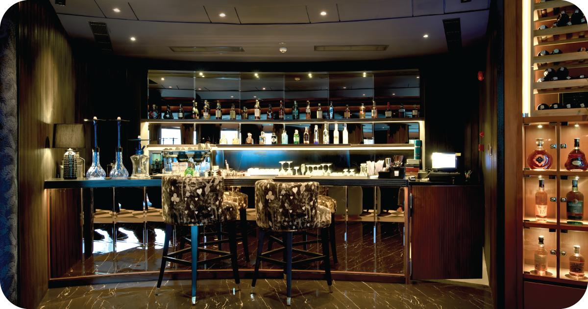 Dim cocktail bar with mirrored backbar and patterned velvet stools