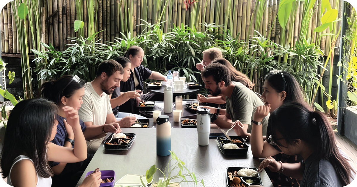 Group dining at long table with bento-style trays and rice