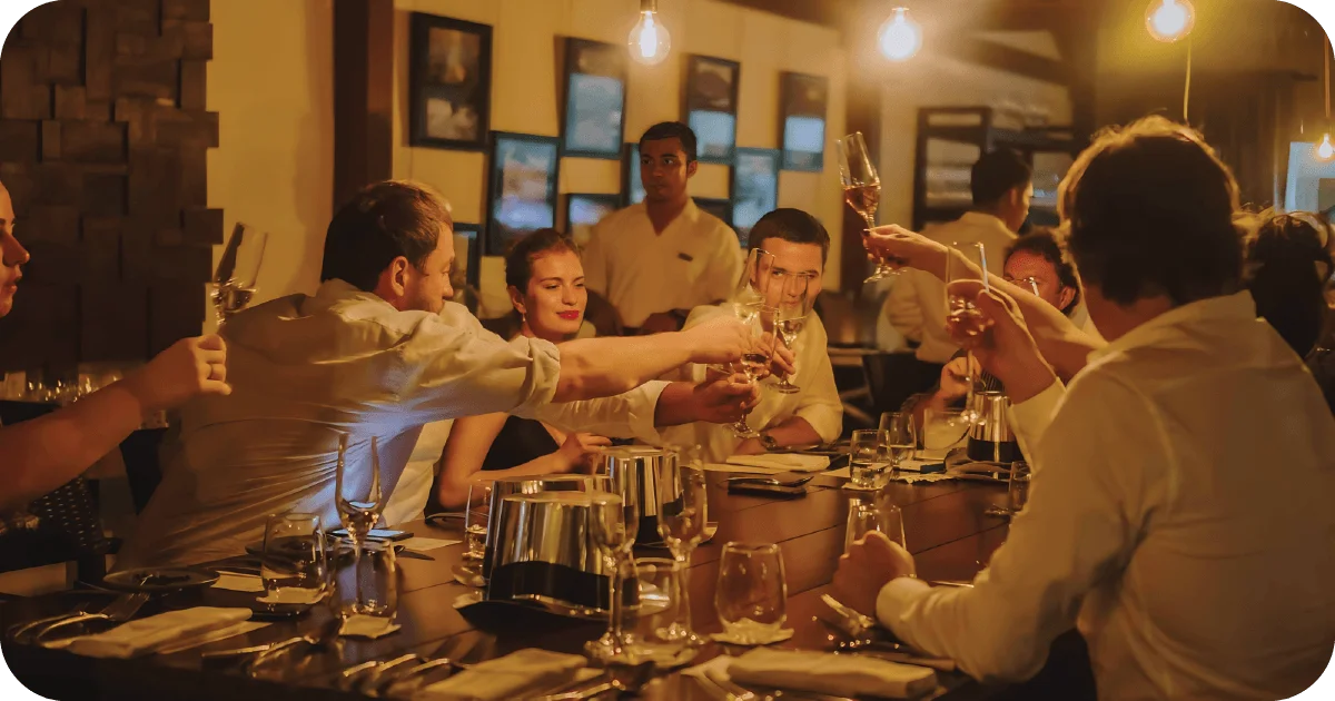 Group toast with champagne flutes in warm, dim dining room