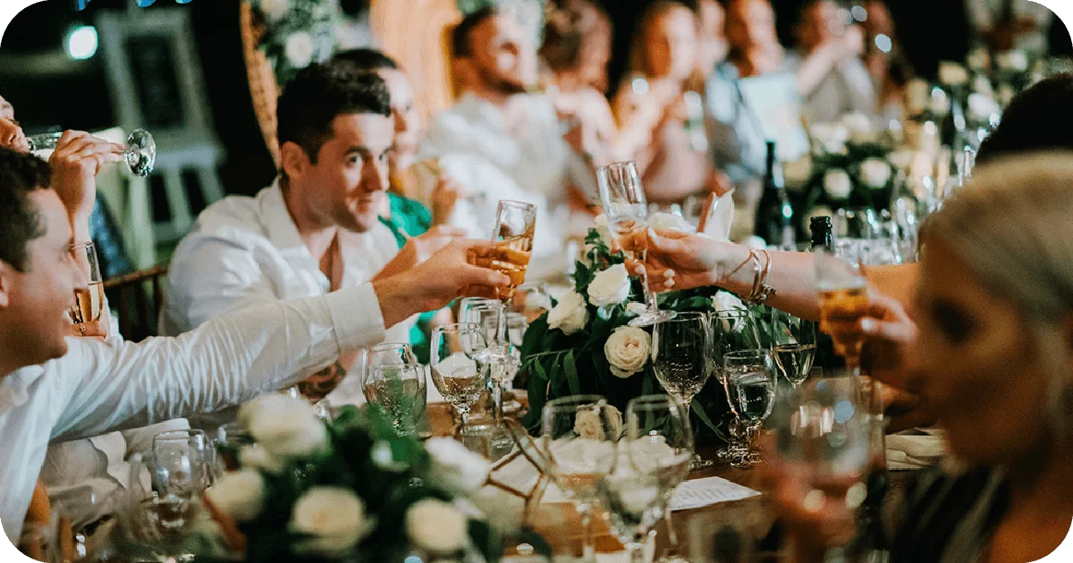 Guests toasting at banquet table with flowers and glassware