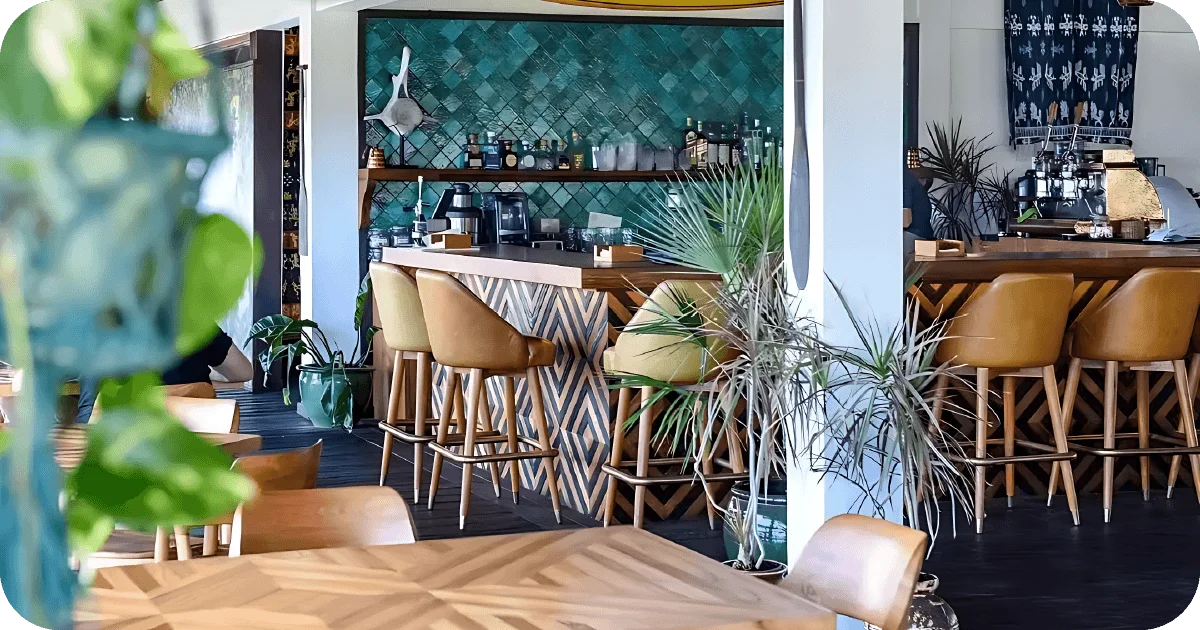 Indoor bar with teal tiled wall and tan barstools