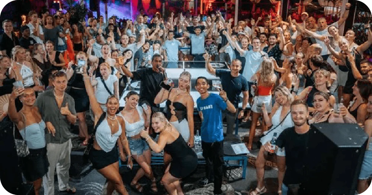 Large crowd posing around stage, hands raised, nightlife energy