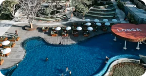 Locca pool deck with green daybeds, white umbrellas, and amphitheater seating