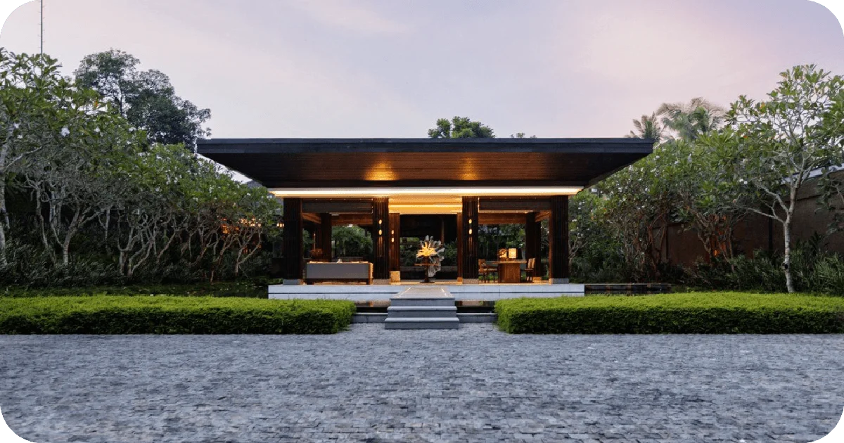 Minimalist open-air pavilion entrance at dusk with landscaped hedges