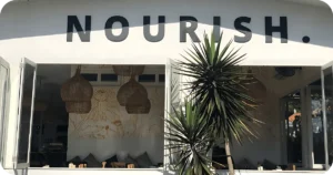 NOURISH. white facade with open windows, rattan lights, floral mural