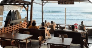 OTHREE open-air seating facing surf, surfboards stacked beside wall