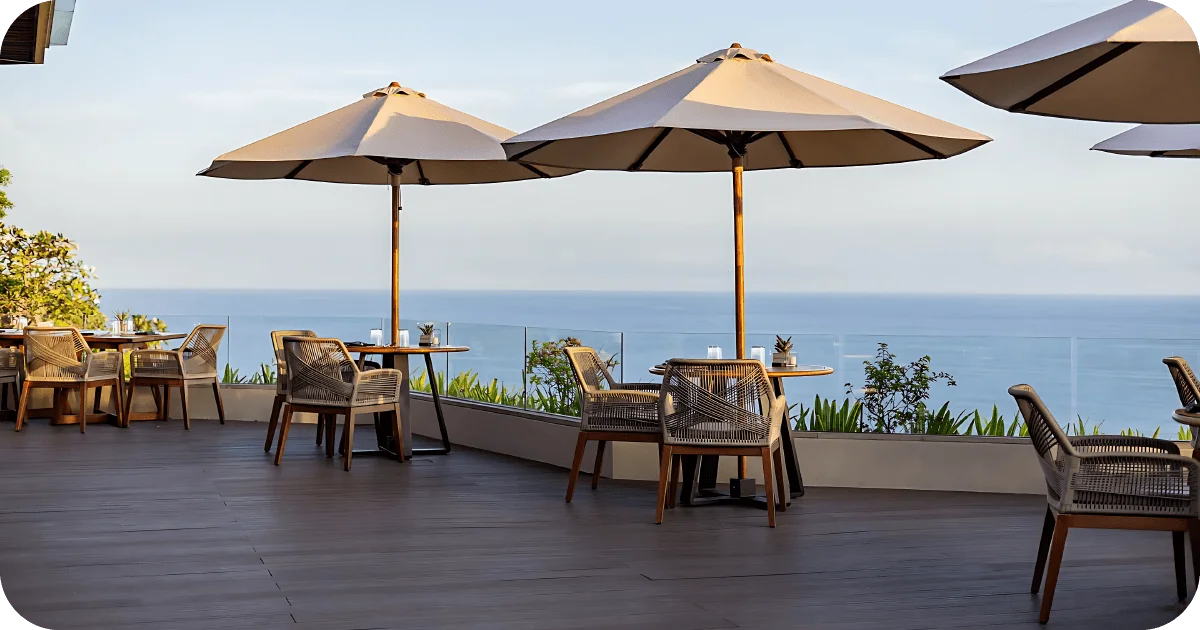 Oceanfront terrace seating with umbrellas and woven chairs
