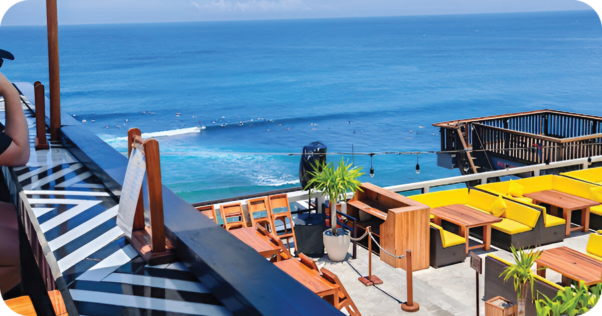 Oceanfront terrace with yellow cushioned booths, bar seating, and surf views