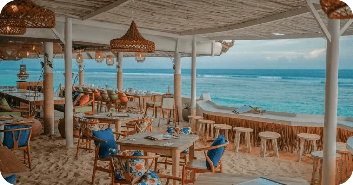Open-air beachfront dining with rattan lamps and ocean views