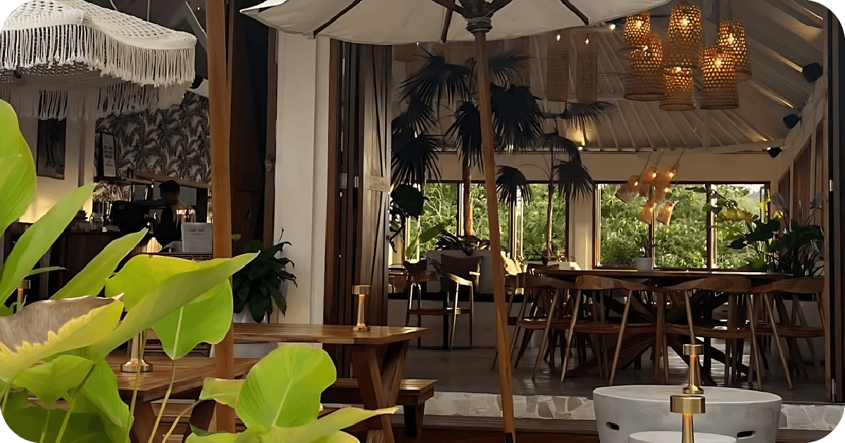 Open-air dining room with umbrellas, rattan pendants, leafy plants