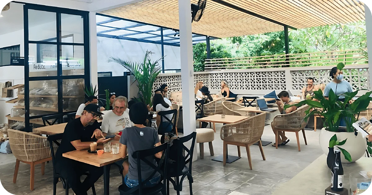 Open-air dining with wicker chairs, potted plants, and slatted canopy
