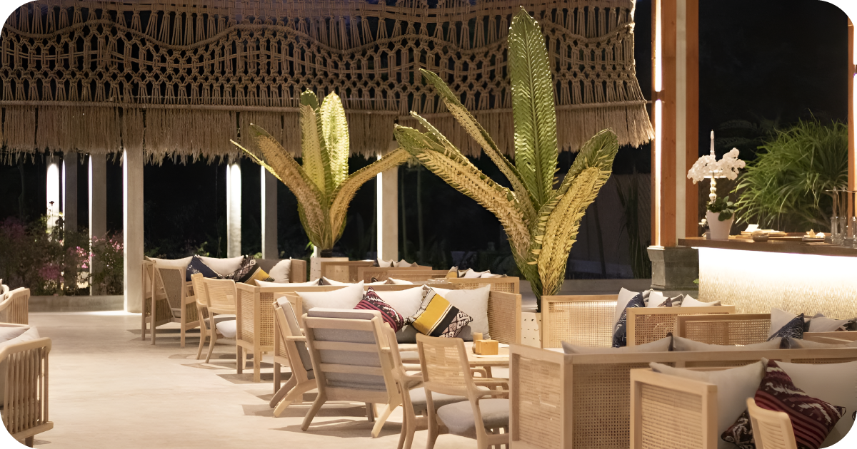 Open-air lounge with rattan seating, woven canopy, and tropical plants