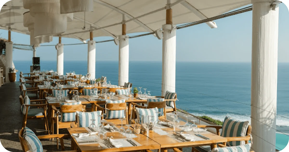 Open-air terrace dining with striped cushions overlooking the ocean