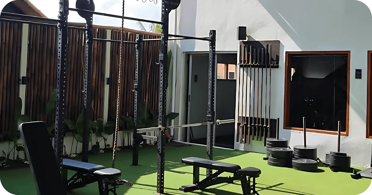 Open outdoor strength area with squat rig, benches and bumper plates