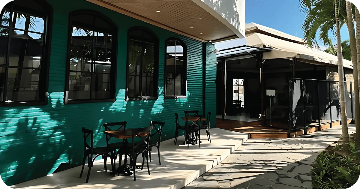 Outdoor patio with teal brick facade and small two-top tables