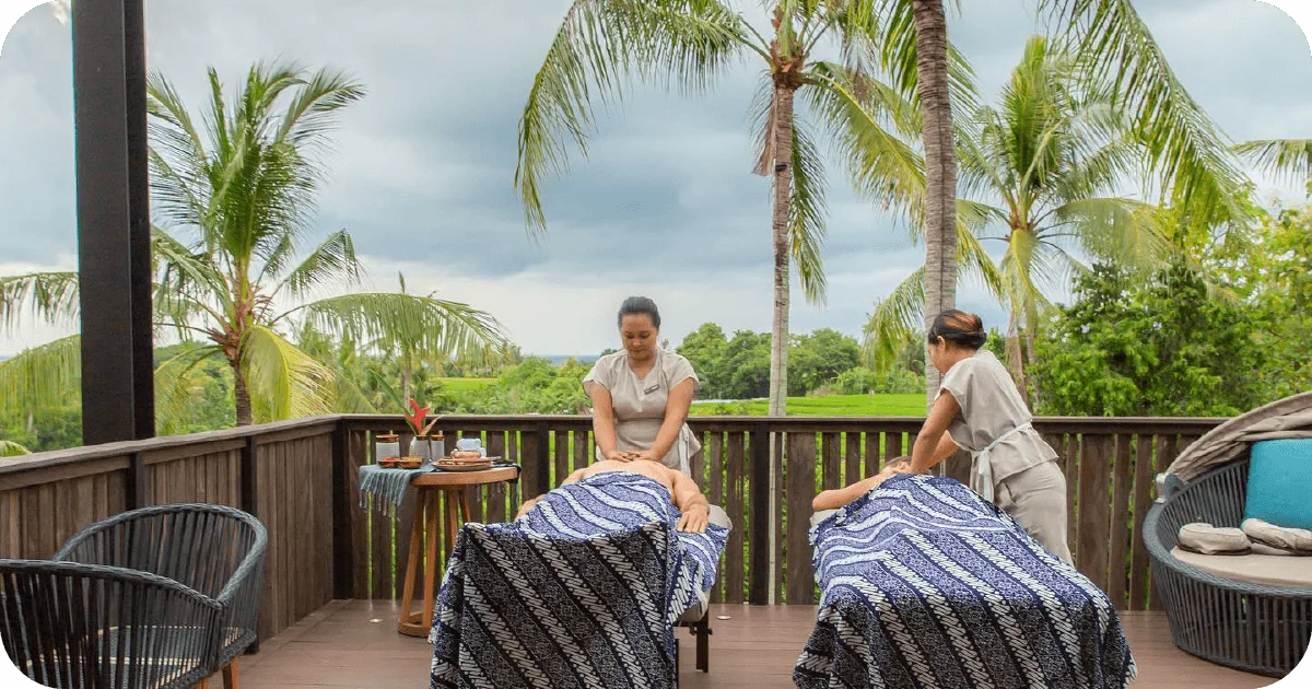 Outdoor twin massage tables on balcony overlooking palms and rice fields