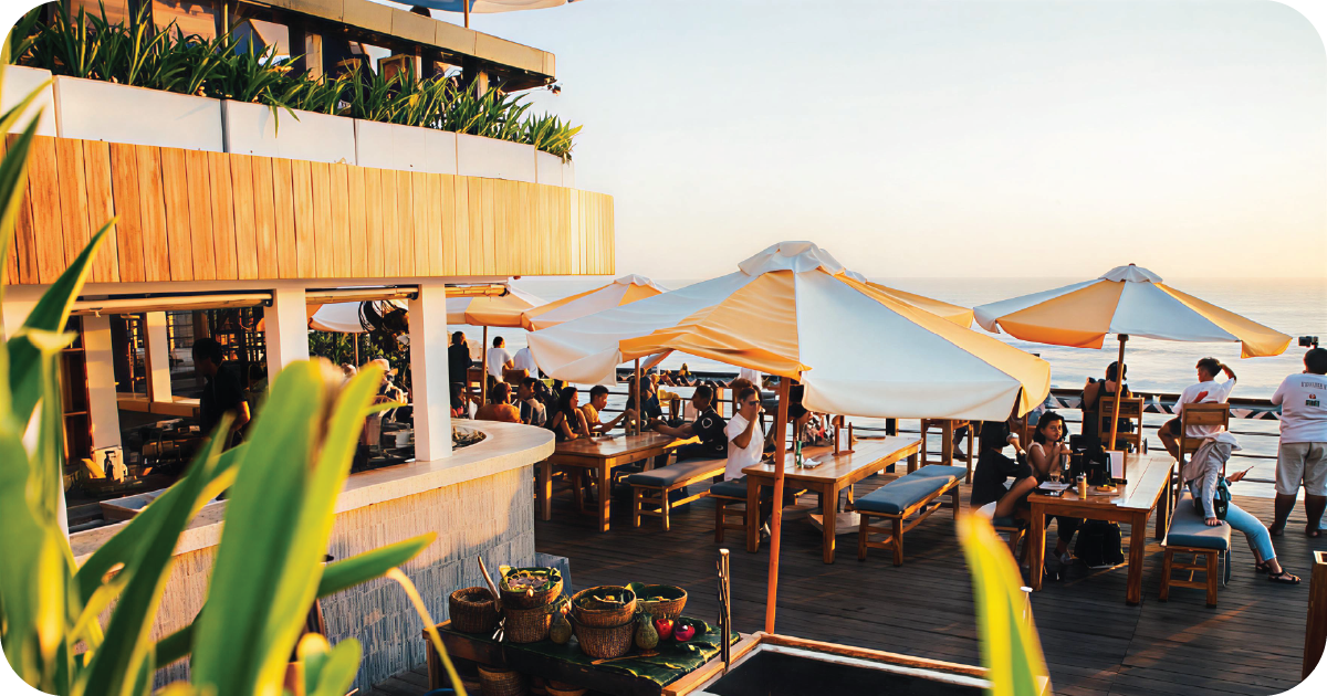 Outdoor wooden tables with striped umbrellas overlooking the sea