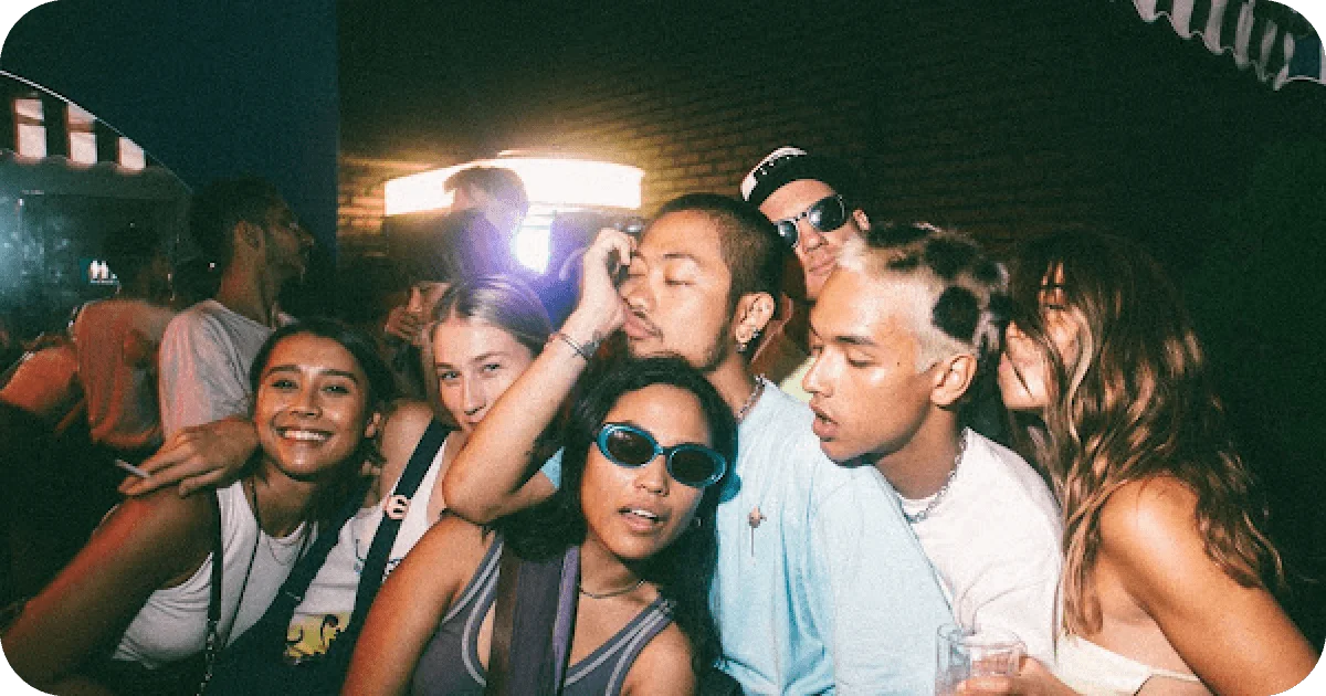 Packed crowd selfie with mixed lighting and retro sunglasses