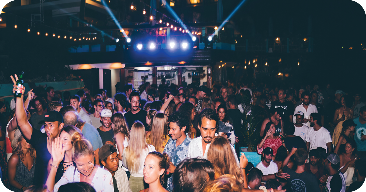 Packed nighttime dance crowd under string lights and stage spotlights