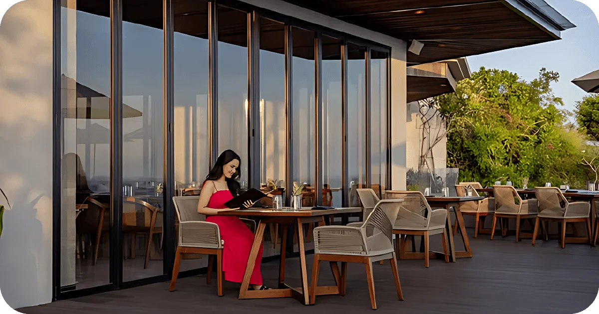 Patio table by glass wall, guest reading menu
