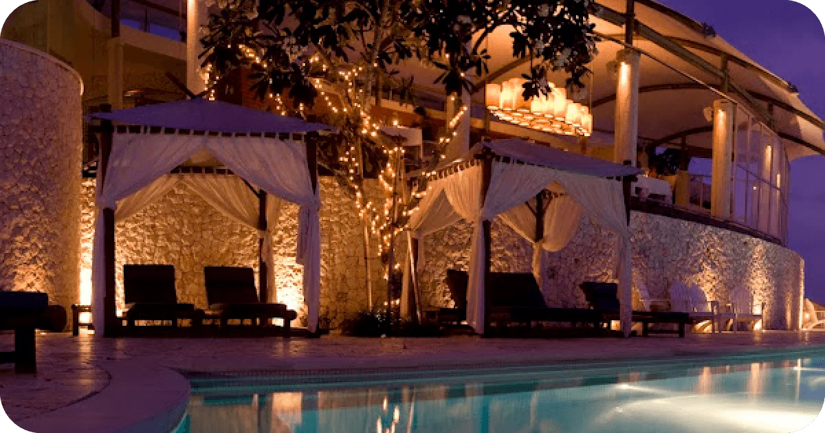Poolside cabanas and twinkling lights beneath the restaurant at night