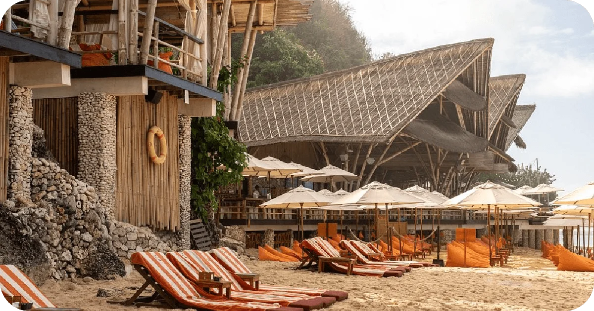 Sandy beach lounge chairs, striped cushions, and bamboo pavilions with umbrellas