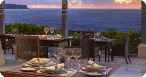 Seaside dining tables set with glassware at sunset