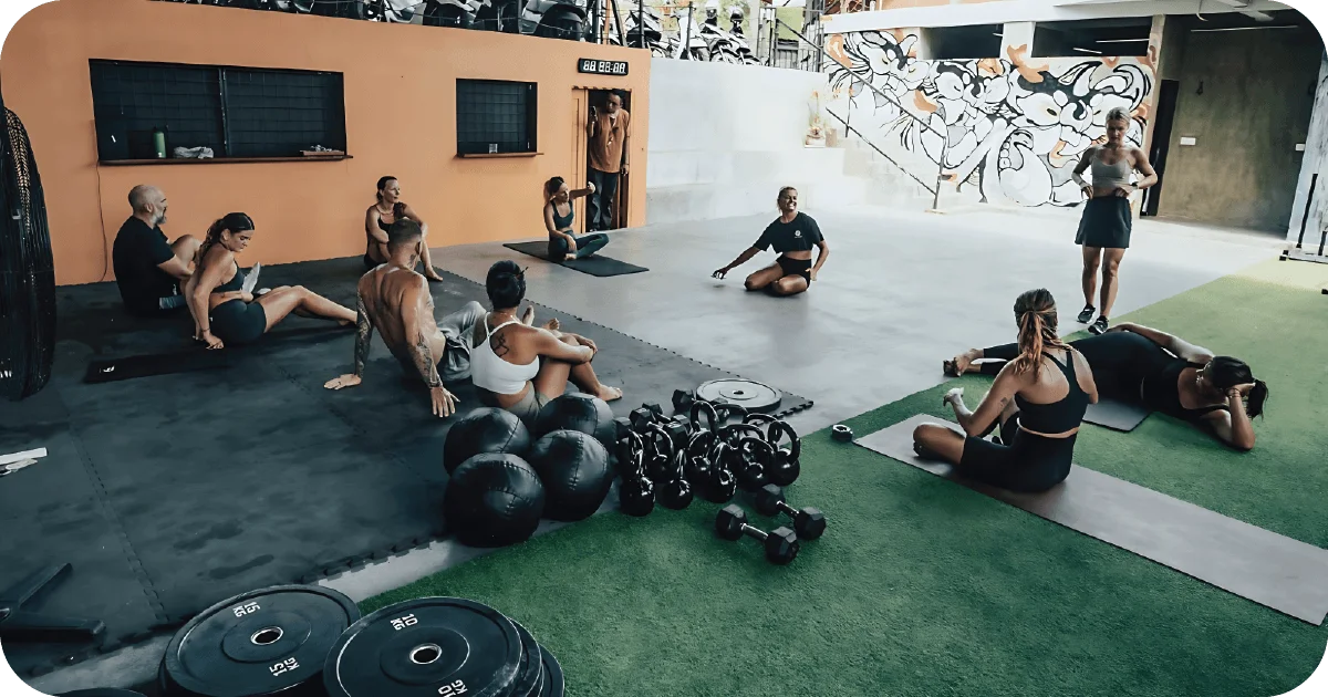 Small group cooldown on mats with dumbbells and slam balls nearby